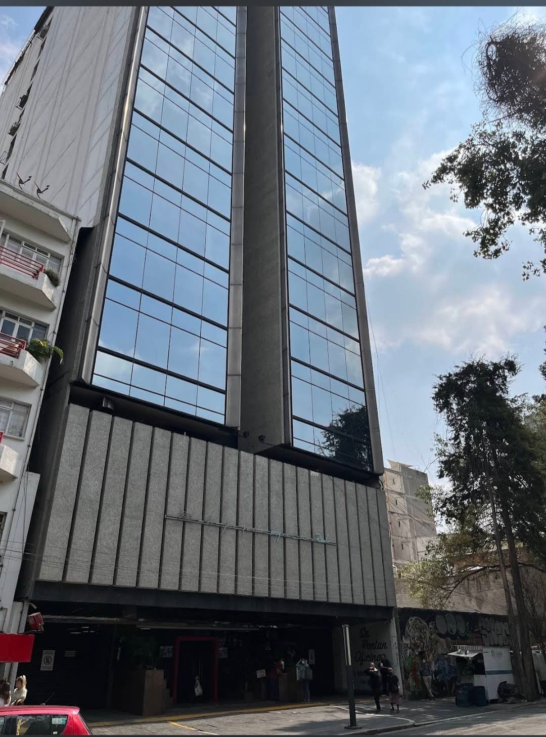 Fachada de cristal y metal del edificio de Clínica Médici con locales en planta baja
