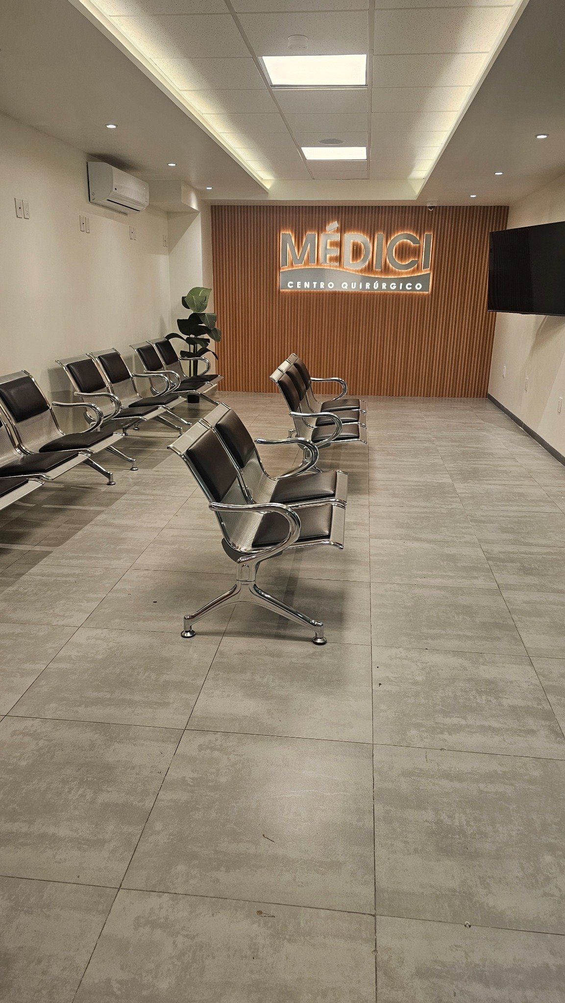 Recepción de Clínica Médici con sillones de espera y muro de madera con el logotipo Médici Centro Quirúrgico